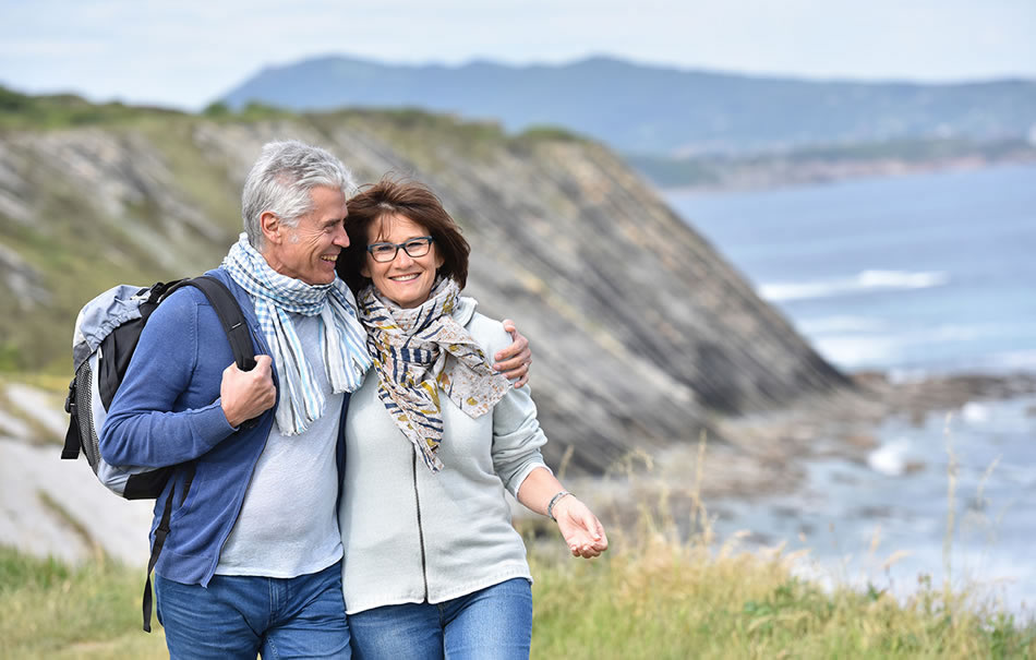 Retired, happy husband and wife walking at a cliffside 